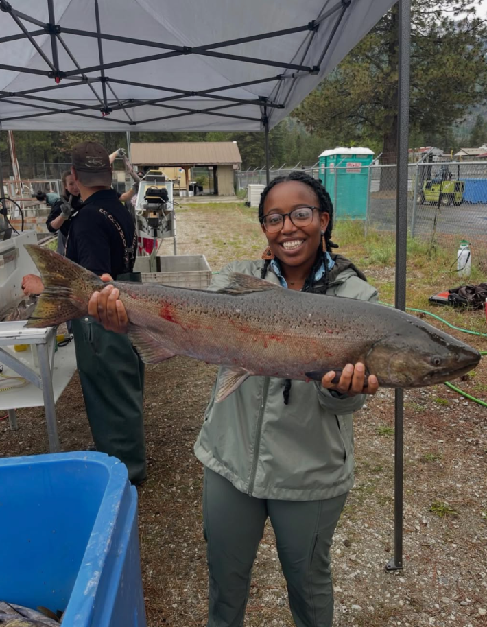 A photo of Kaesee Bourne, a former fish and wildlife biologist with the US Fish and Wildlife Service, holding a large fish